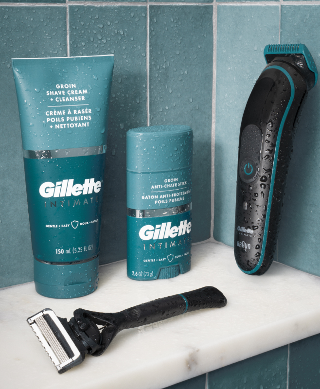 Two razors, a bottle, and an anti-chafe stick on a bathroom shelf.